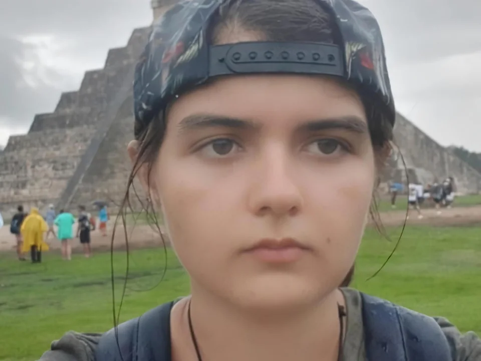 Portrait of Paula Ruiz-Rodriguez in a backwards cap, with a stepped pyramid behind her